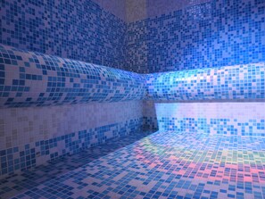 Une pièce dont les murs et le sol sont recouverts de carreaux bleus, créant ainsi un motif uniforme.