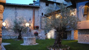 A stone building with a garden featuring a tree and potted plants. - Residenza d'epoca & Spa Il Cerchio di Lullo (Fumone)