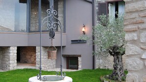 A stone building with a circular stone fountain in the center, surrounded by a well-maintained lawn. - Residenza d'epoca & Spa Il Cerchio di Lullo (Fumone)