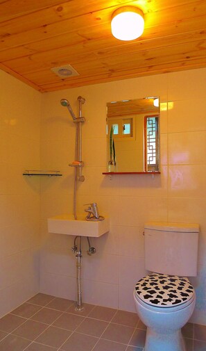 A bathroom with a wooden ceiling, a white sink, a toilet, and a shower. - HanOK Guest House 201 (Seoul)