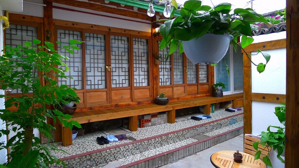 A traditional Japanese room with tatami flooring, a wooden bench, and a hanging plant. - HanOK Guest House 201 (Seoul)
