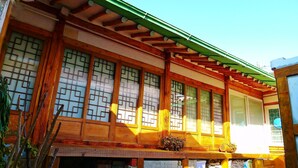 A traditional Japanese building with wooden architecture, large sliding doors, and a green roof. - HanOK Guest House 201 (Seoul)