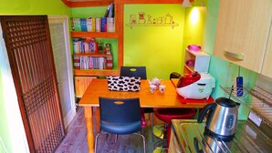 A compact kitchen with a dining table, chairs, a coffee machine, a kettle, and a bookshelf filled with books. - HanOK Guest House 201 (Seoul)