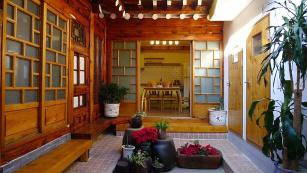 A traditional wooden interior with sliding doors, a tiled floor, and various potted plants. - HanOK Guest House 202 (Seoul)
