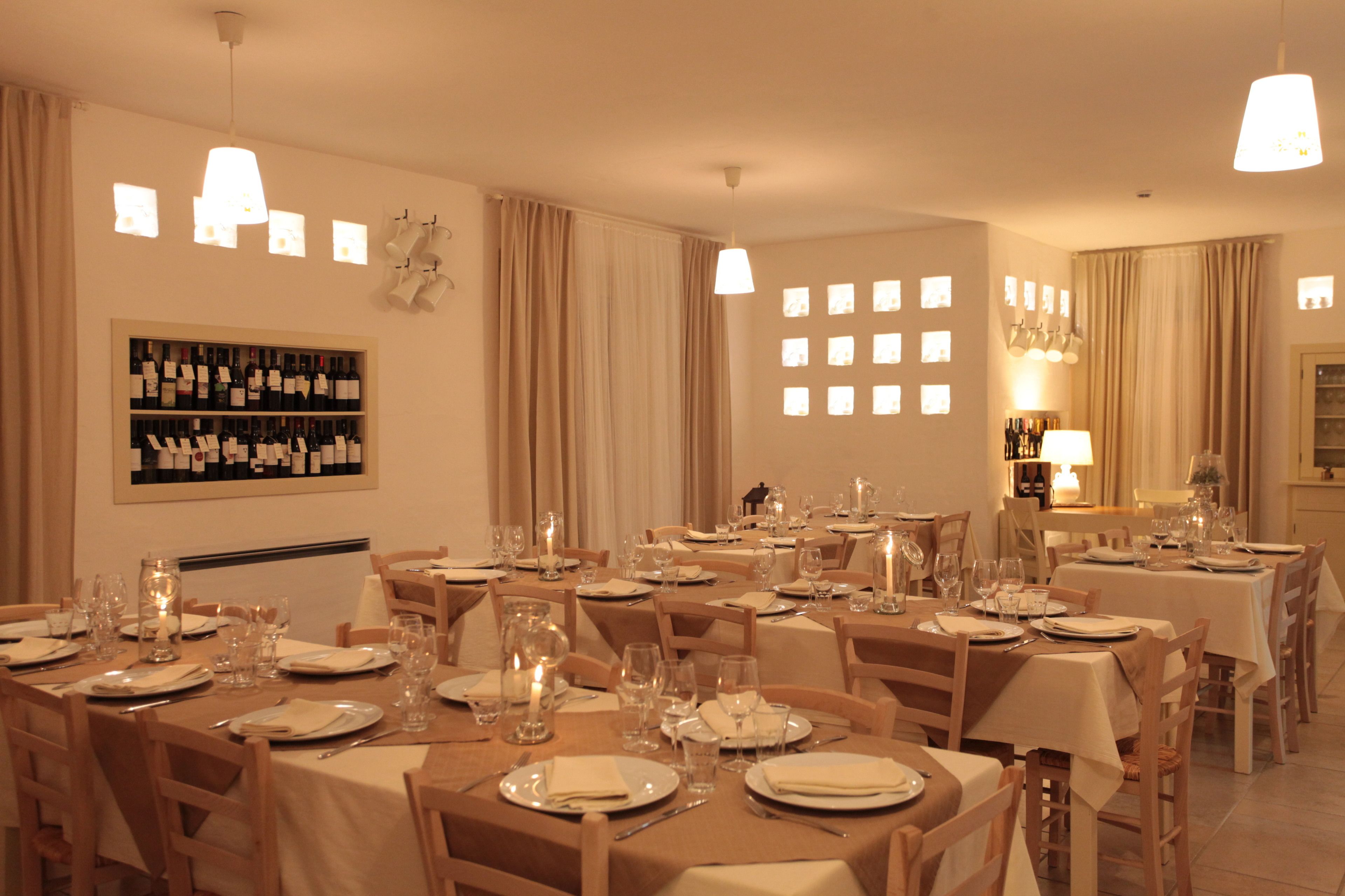 A dining area with multiple tables set for service, a wine rack, and a chandelier.