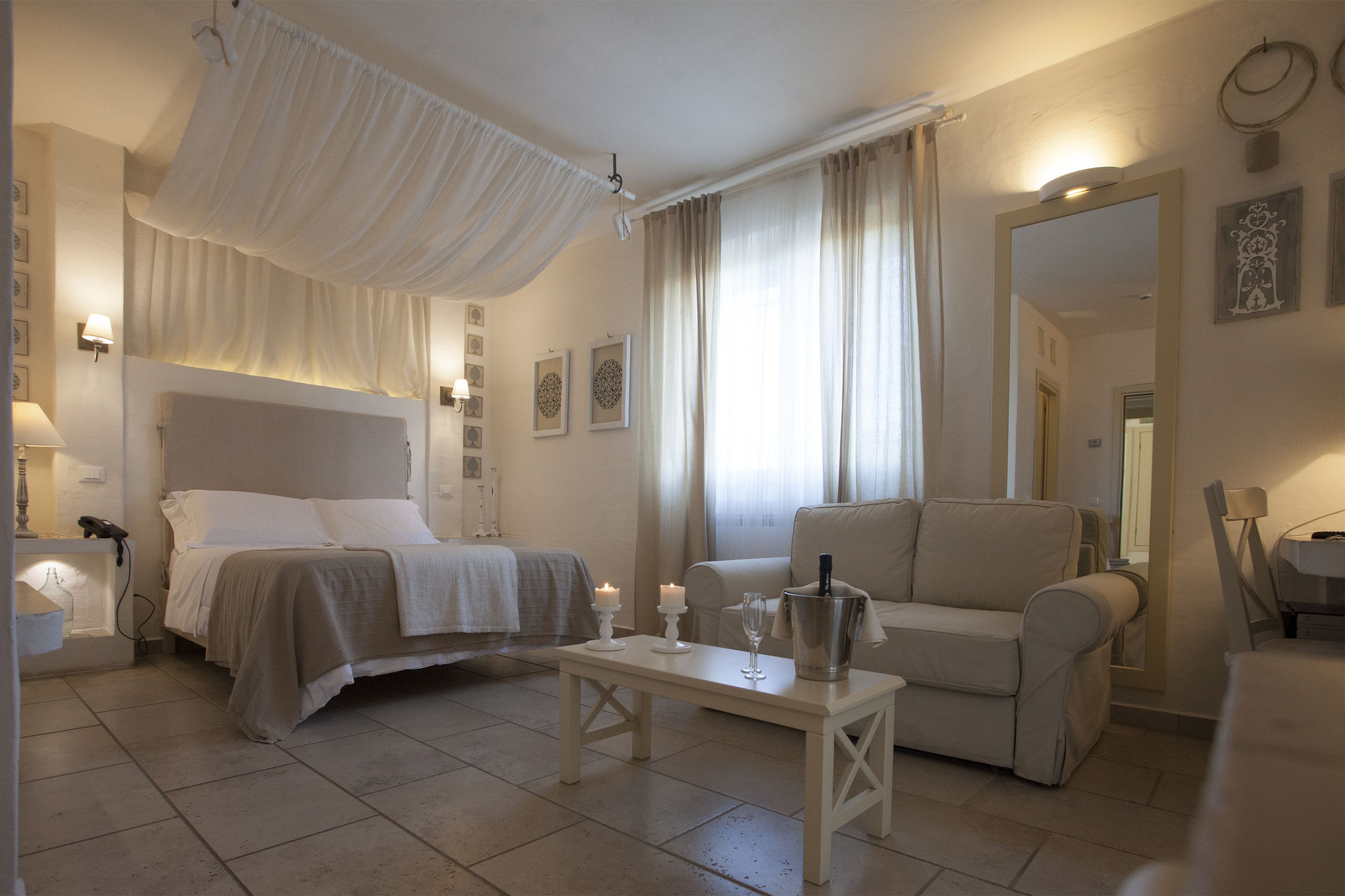 Ein Hotelzimmer mit einem Bett, einer Couch, einem kleinen Tisch mit Kerzen und einem Kronleuchter.