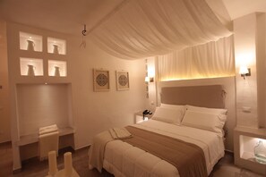 A hotel room with a large bed, bedside tables, a bench with a towel, and wall-mounted artwork.