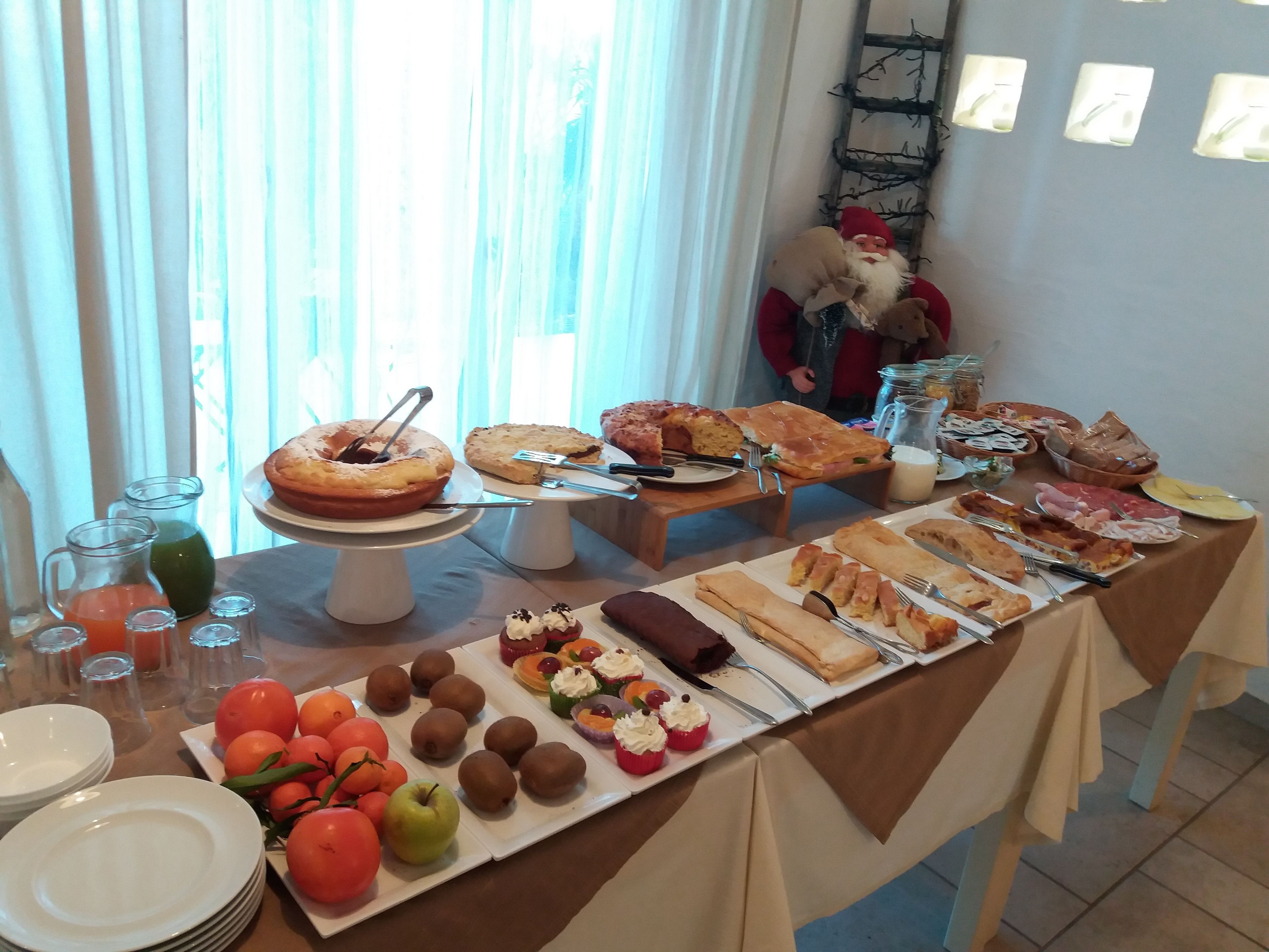 A buffet table with various food items and a Santa Claus decoration.