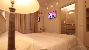 Habitación de hotel con cama, televisión, baño con lavabo y espejo, y una lámpara.