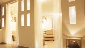 Una habitación con sofá, una silla y una lámpara. Hay cortinas y una ventana.