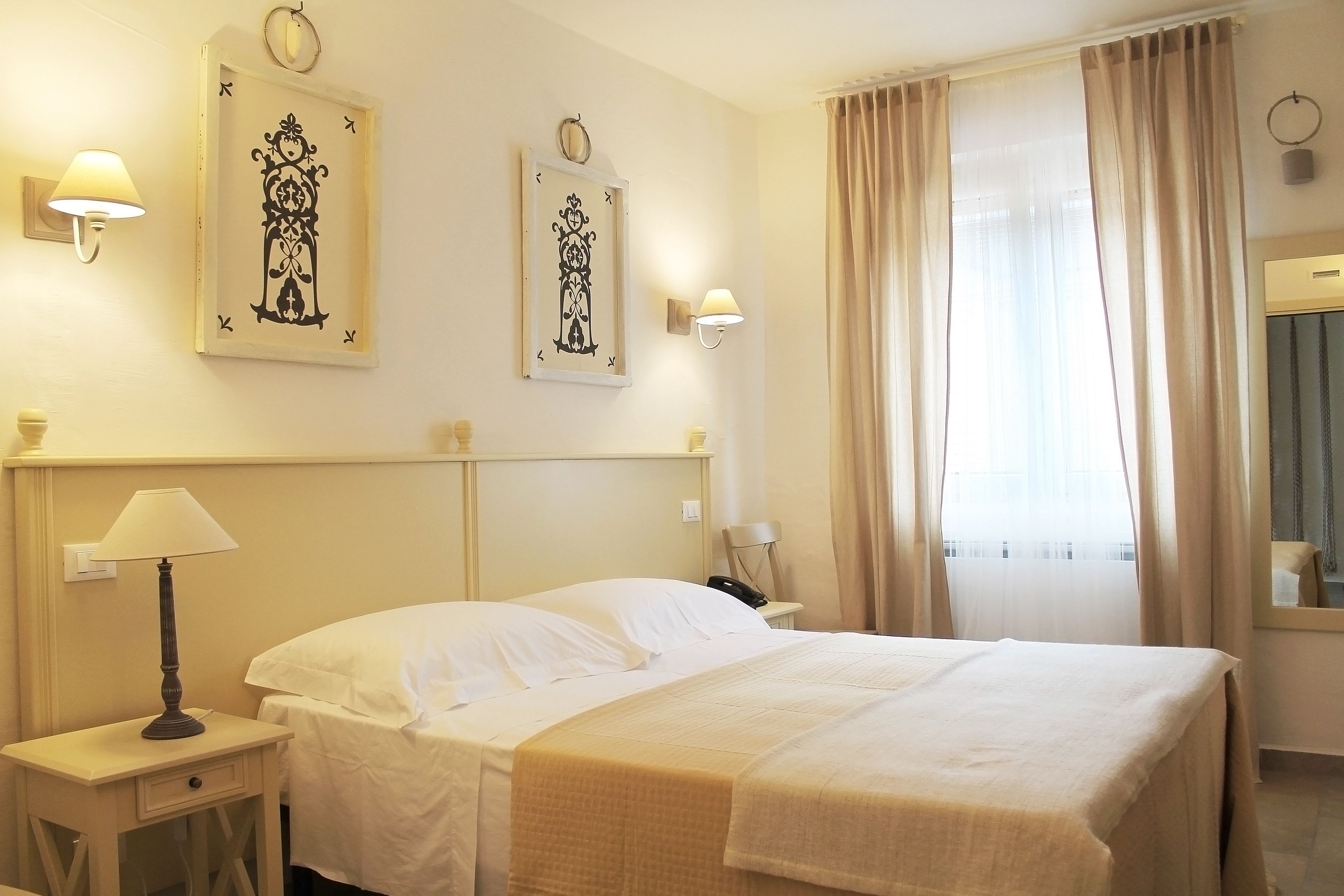 Une chambre d’hôtel comprenant un lit, des lampes de chevet, une table de chevet et des œuvres d’art accrochées au mur.