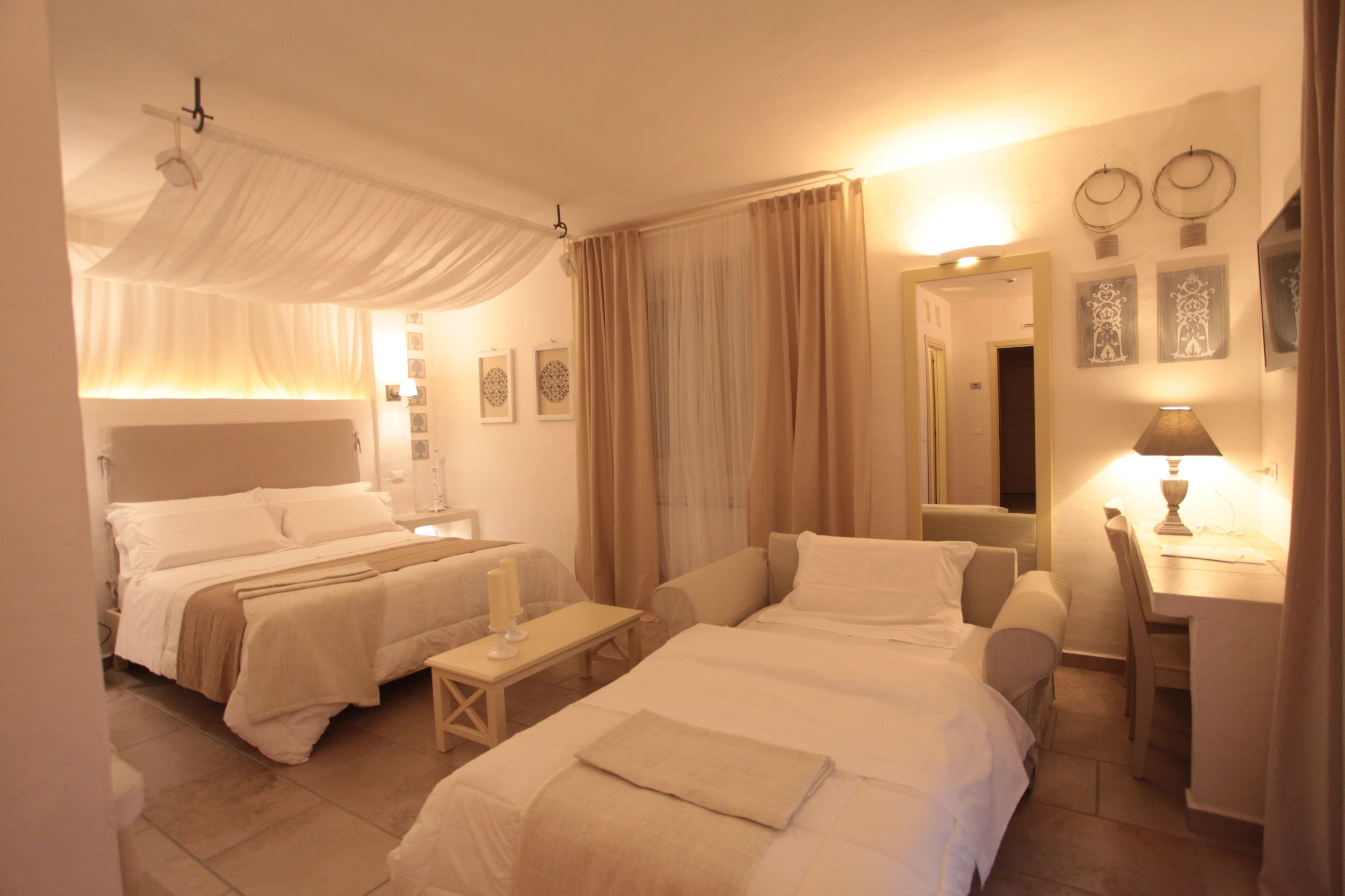 A hotel room with two beds, a desk, a chair, and a small table.