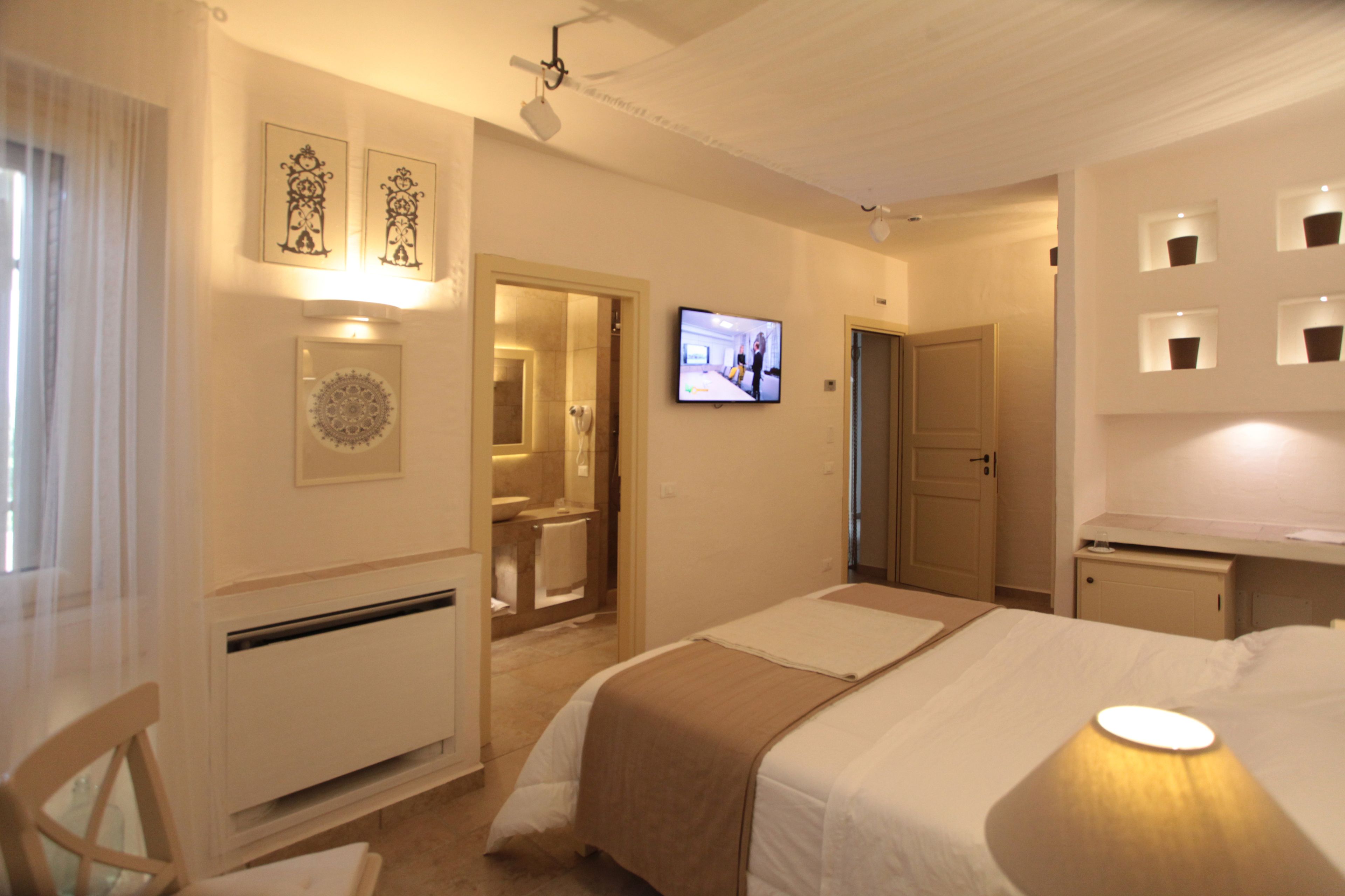 A hotel room with a bed, a television, a bathroom, and a desk.