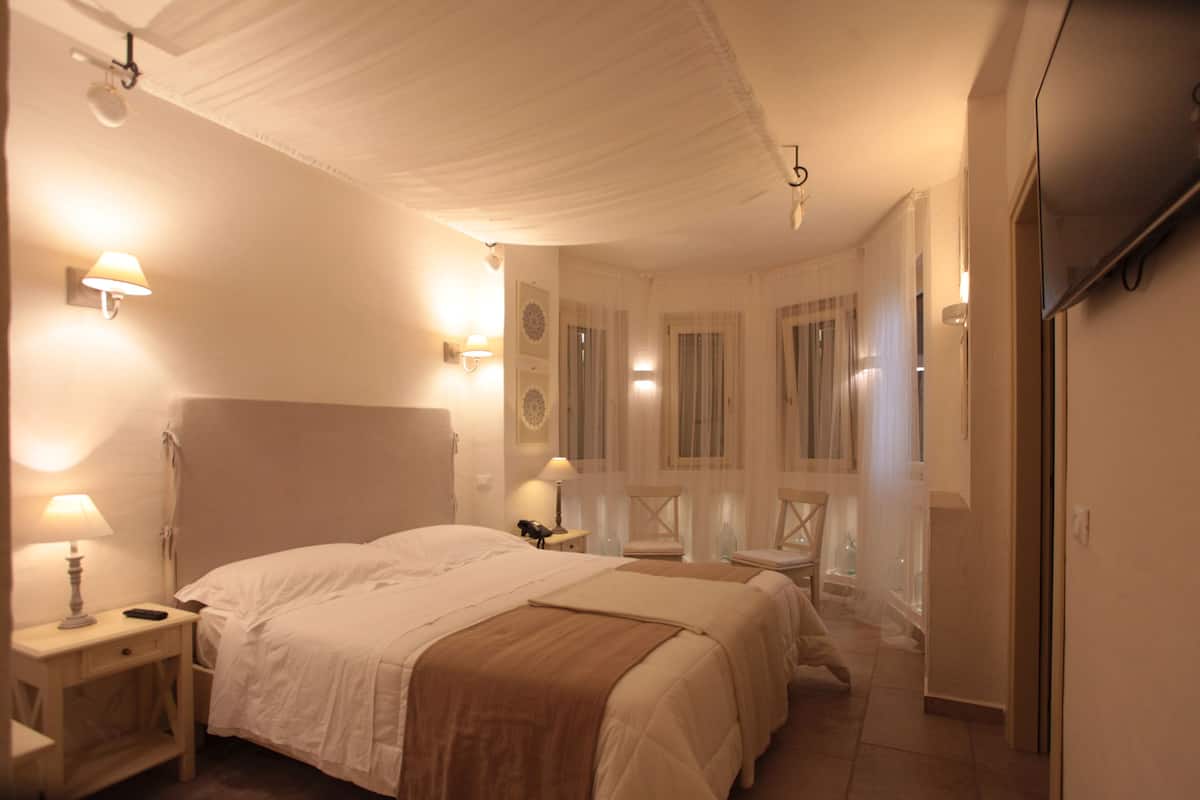A hotel room with a large bed, bedside tables with lamps, a wardrobe, and a mirror.