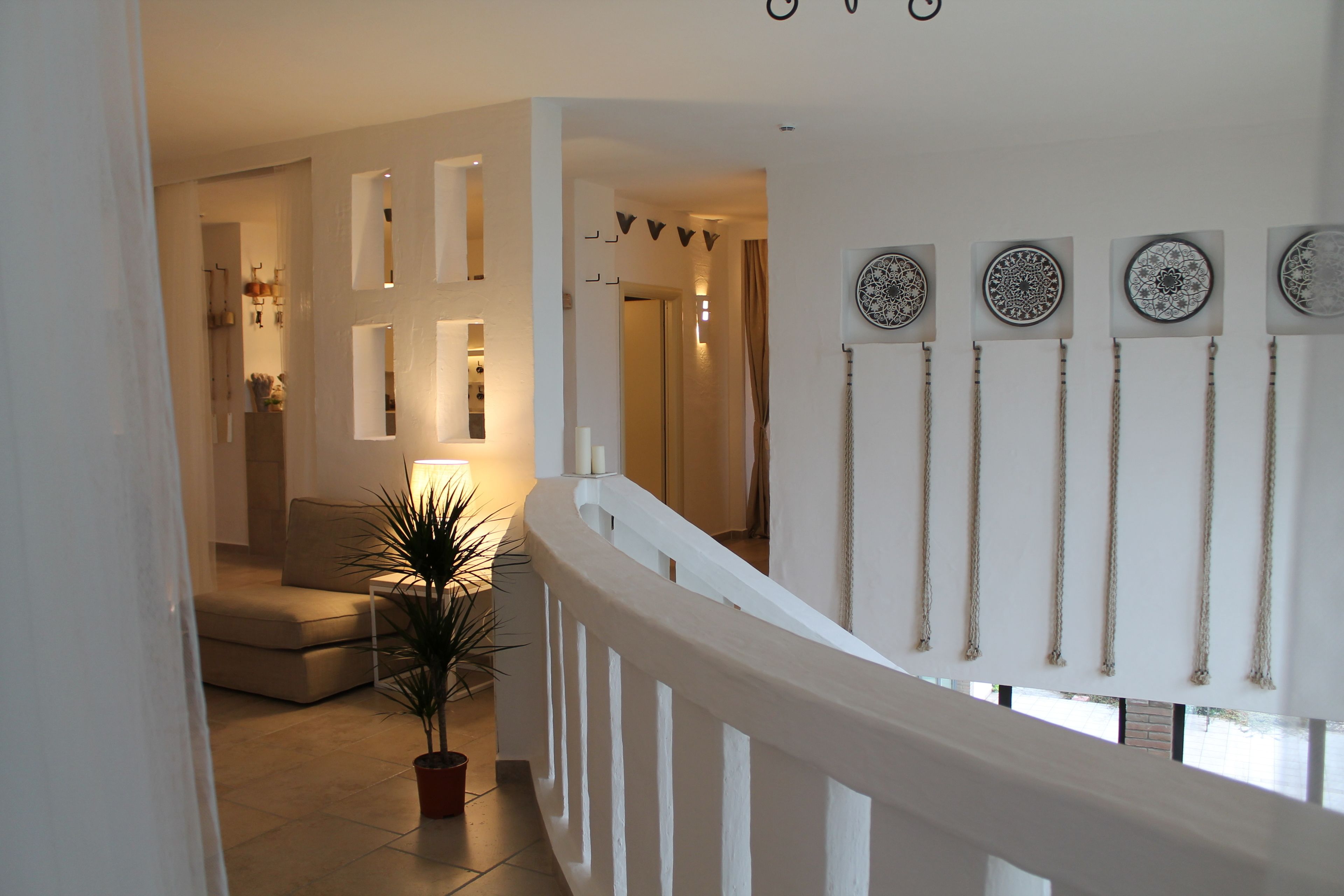 A staircase with a white railing, a potted plant, and wall-mounted decorative plates.