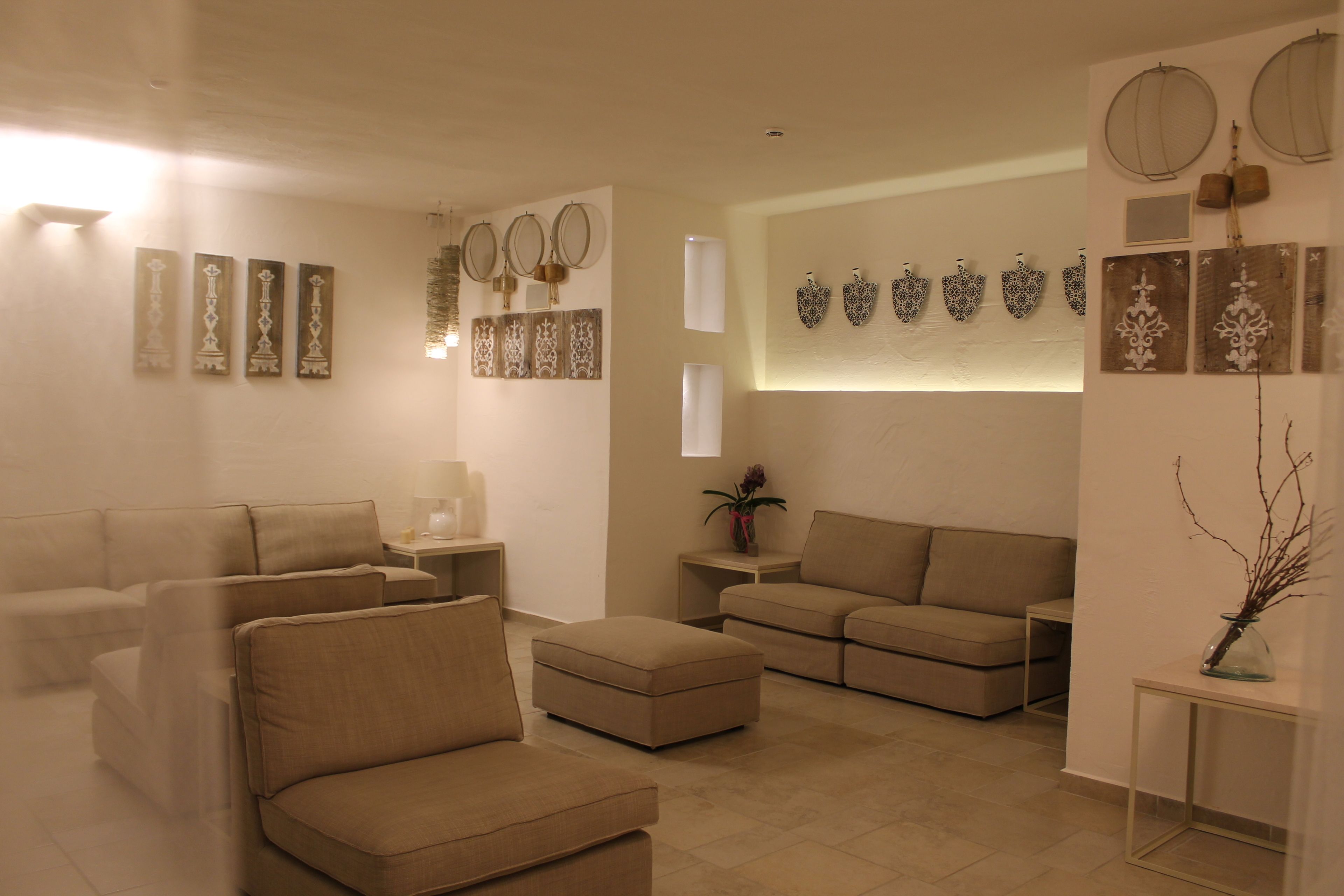 Un salon moderne avec des canapés de couleur beige, une table basse et des œuvres d’art décoratives accrochées au mur.