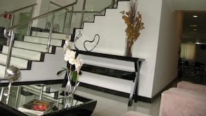 A modern interior with a staircase, a glass coffee table, and a vase with flowers. - Terraço Hotel (Tres Pontas)