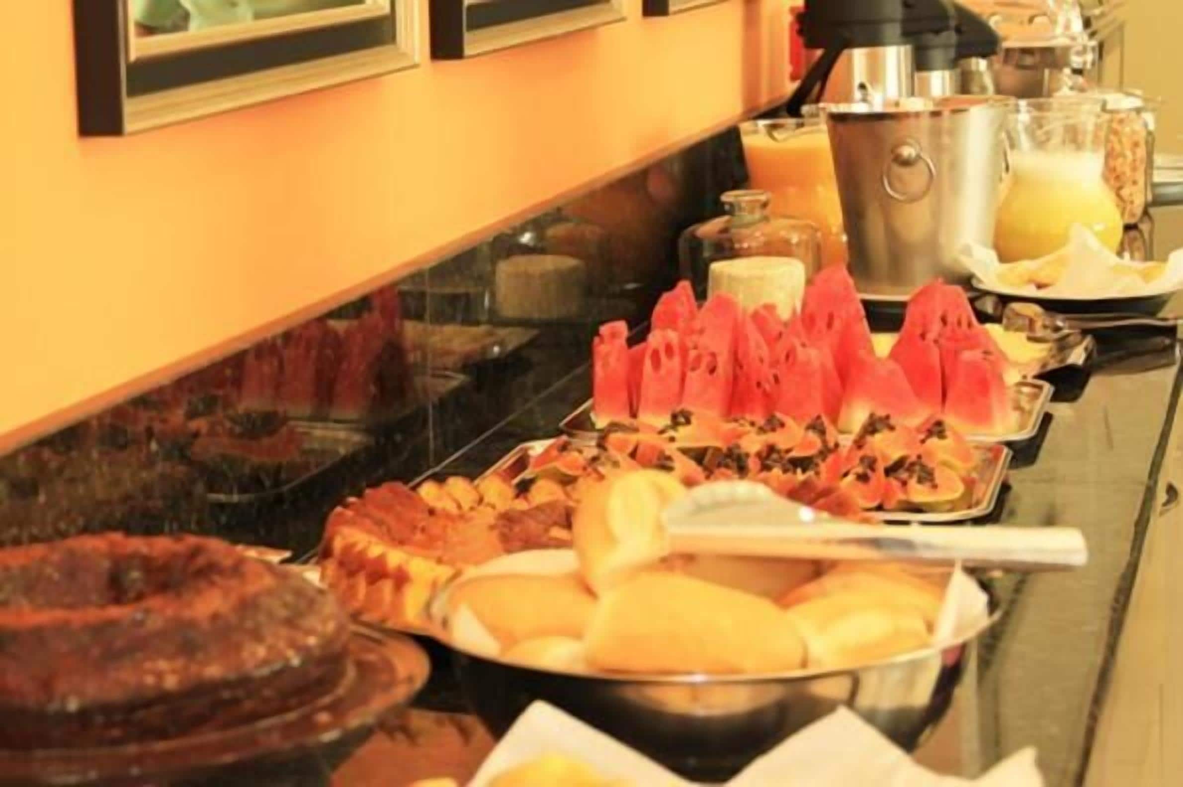 Un bufé con diversos alimentos, entre ellos frutas, pasteles y un pastel.