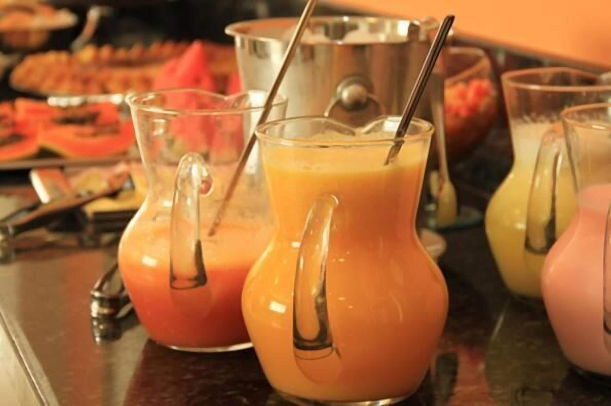 A buffet with various food items and drinks, including orange juice in pitchers.