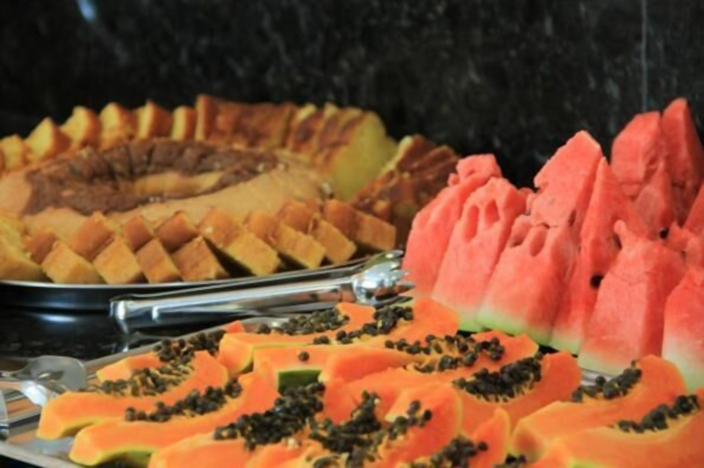 A buffet with sliced fruits and a cake.