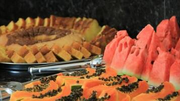 Un buffet avec des fruits coupés en tranches et un gâteau.