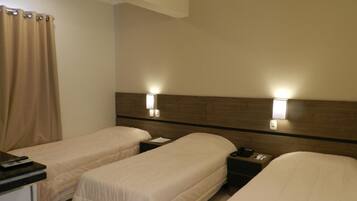 Ett hotellrum med två separata sängar, ett skrivbord med en telefon och en gardin.