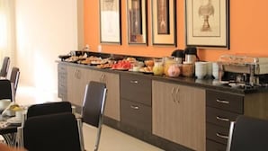 A kitchen area with a counter displaying various food items and kitchen appliances. There are framed pictures on the wall and a coffee machine on the counter. - Terraço Hotel (Tres Pontas)