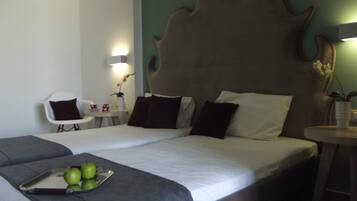 A hotel room with a large bed, a bedside table with a lamp, a chair, and a small table with a plant.
