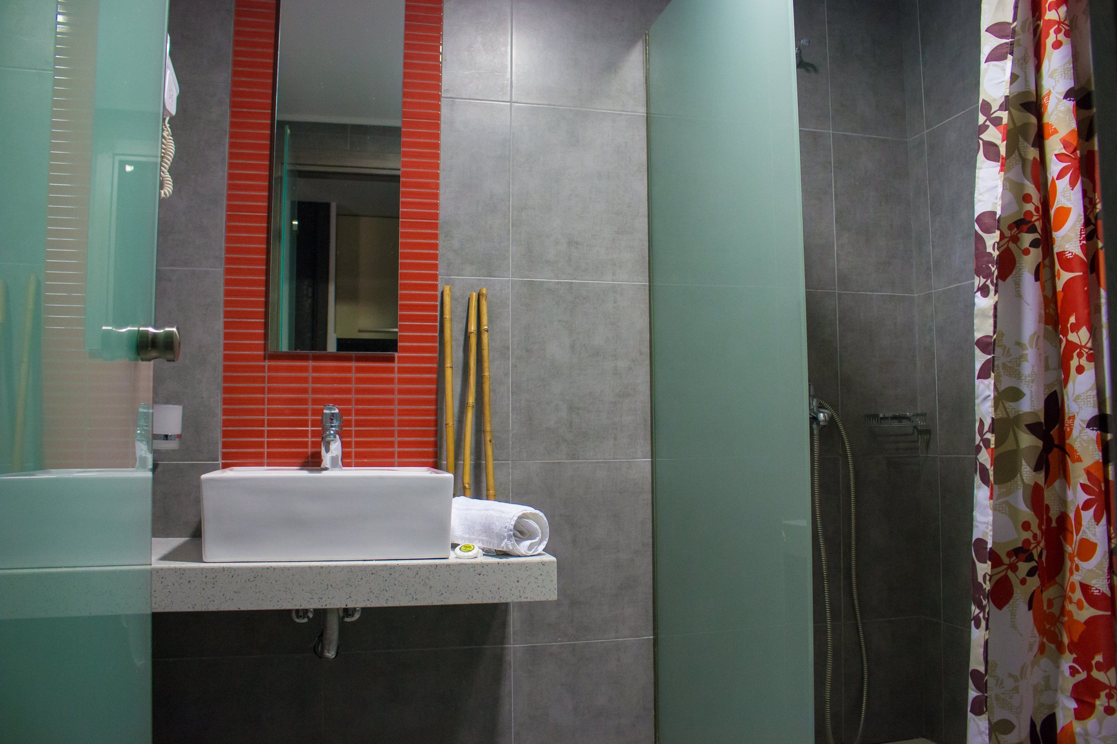 Een badkamer met een witte wastafel, spiegel en douche.