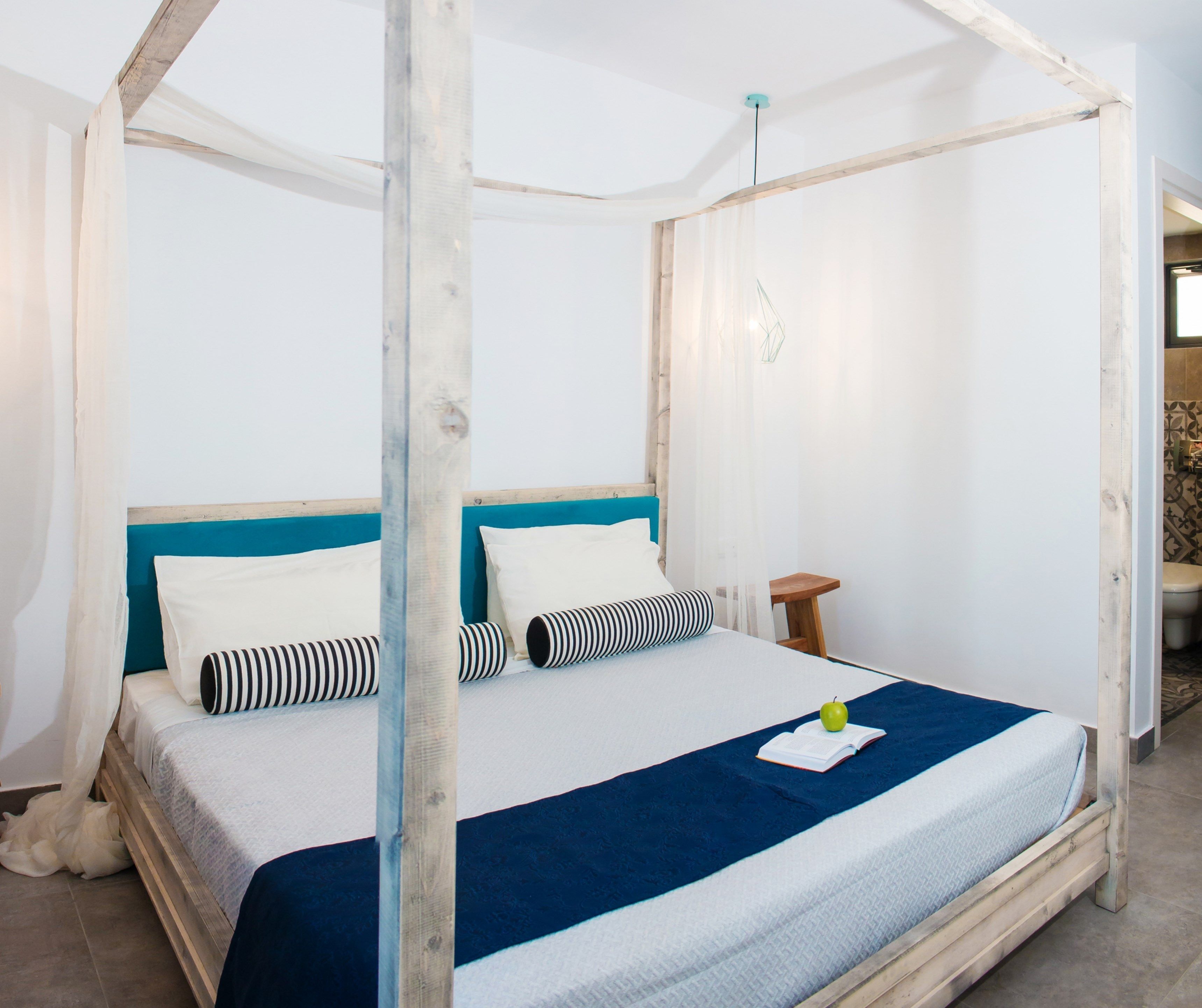 Un lit à baldaquin avec une literie blanche et bleue, une tête de lit en bois et une petite table de chevet avec une lampe.