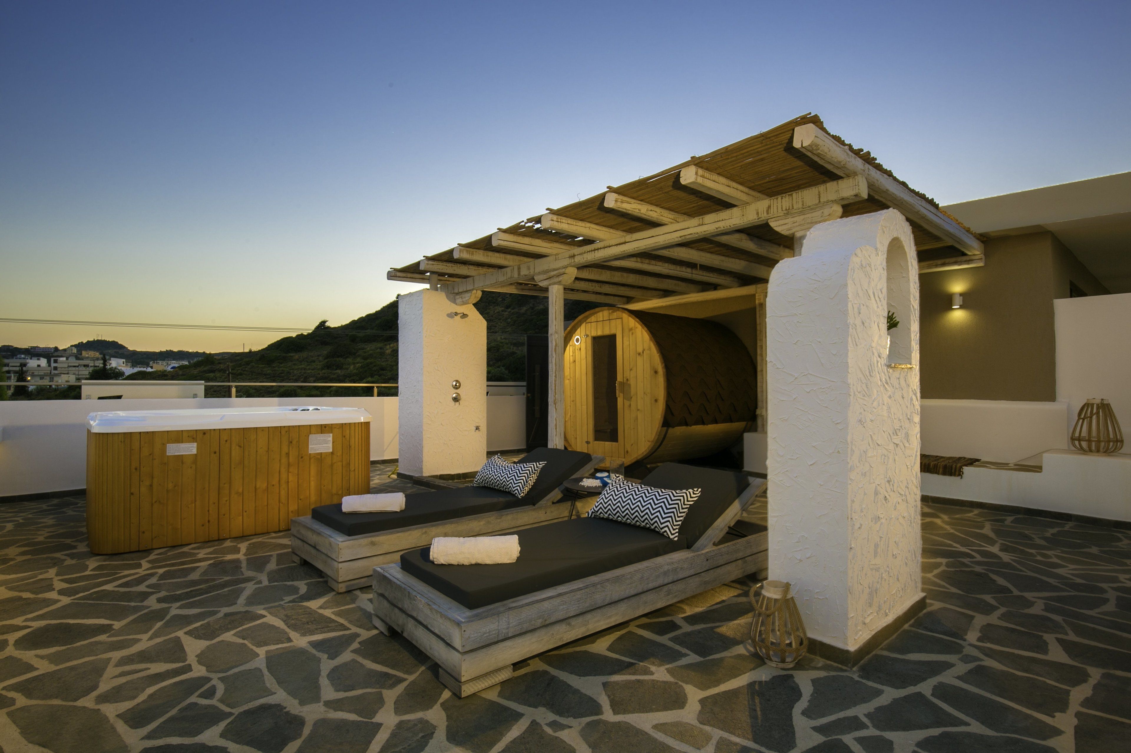 A rooftop relaxation area with two sun loungers, a hot tub, and a pergola structure.