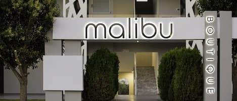 A modern building with a prominent 'malibu' sign above the entrance, a staircase leading up, and a 'boutique' sign on the right.