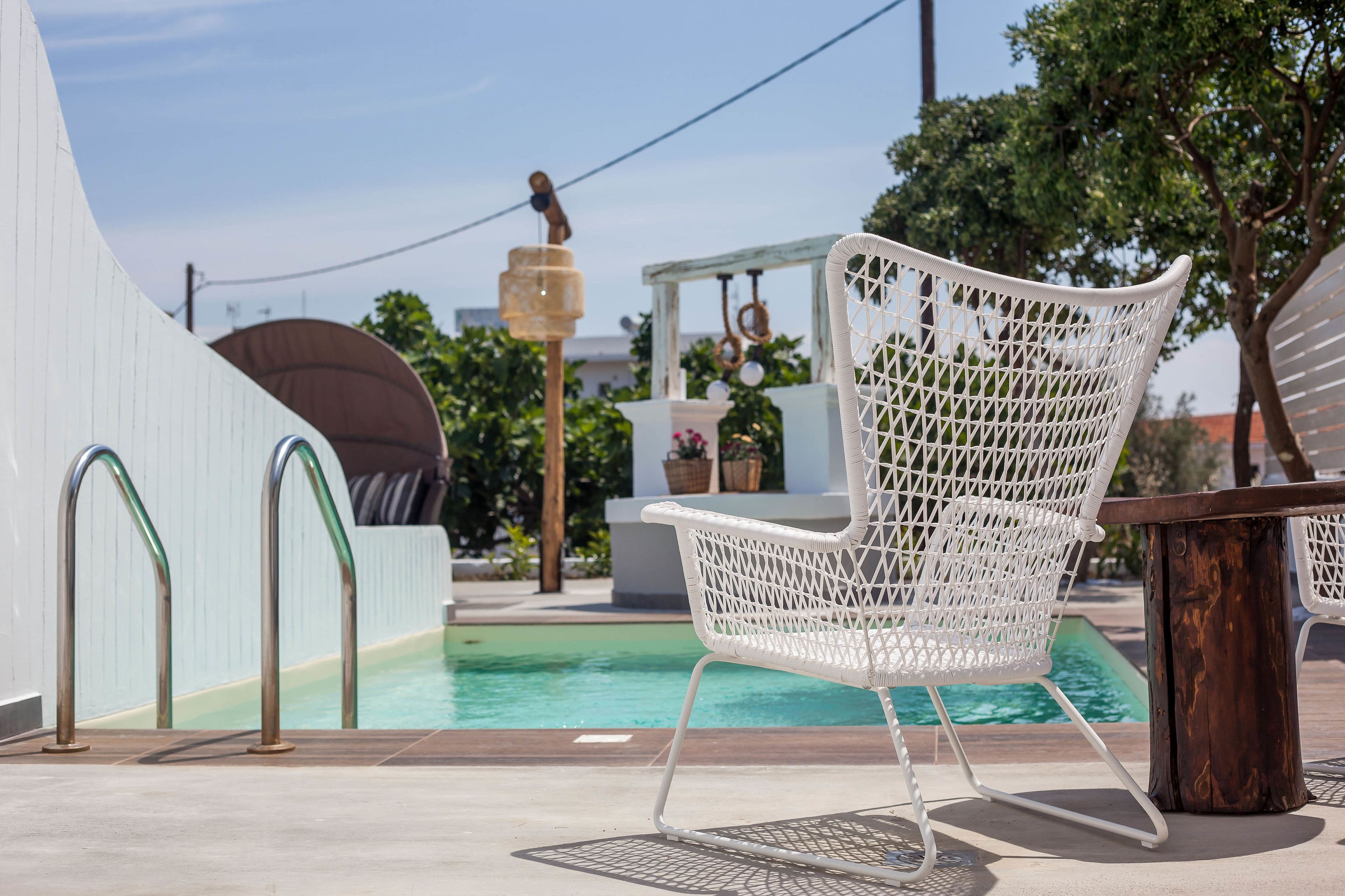 A poolside area with a white wicker chair, a wooden table, and a clear view of the pool.