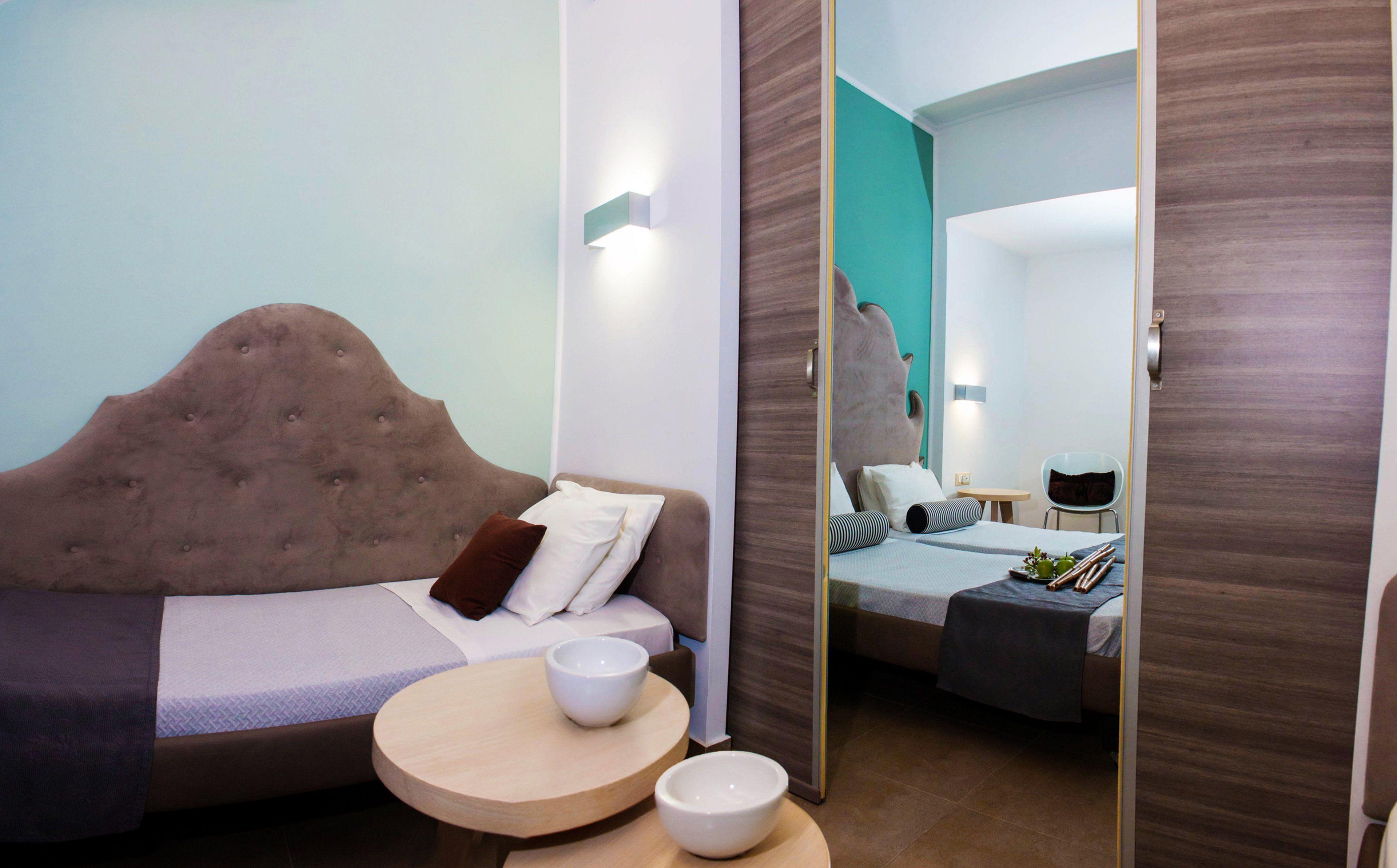 Ein modernes Hotelzimmer mit einem großen Bett, einem kleinen runden Tisch und einem Spiegel.