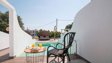 A poolside area with a round table, a wicker chair, and a glass of orange juice.