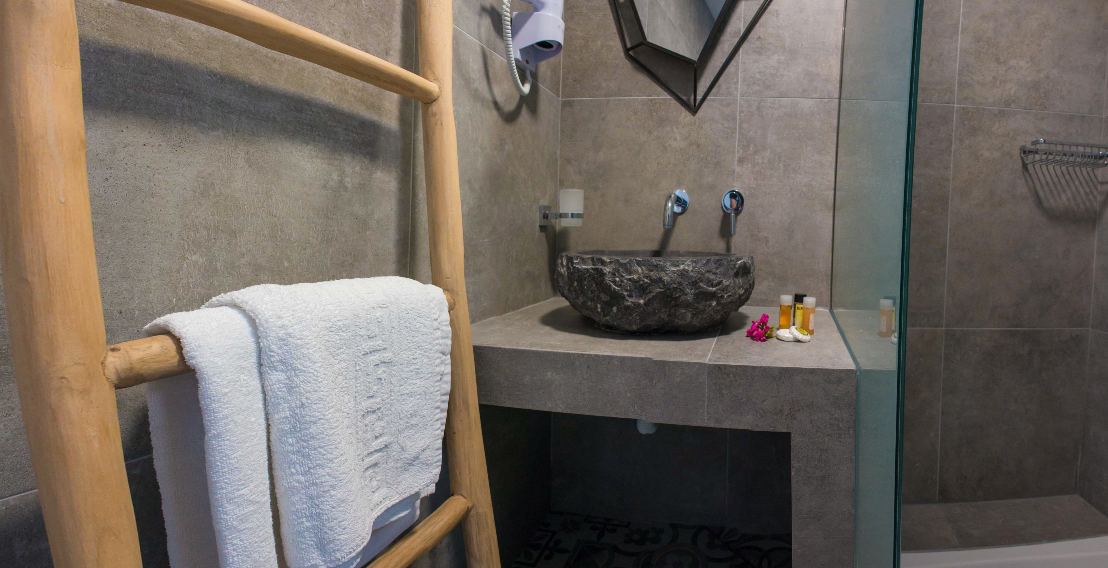 Un bagno con asciugamano in legno, lavabo in pietra e box doccia in vetro.