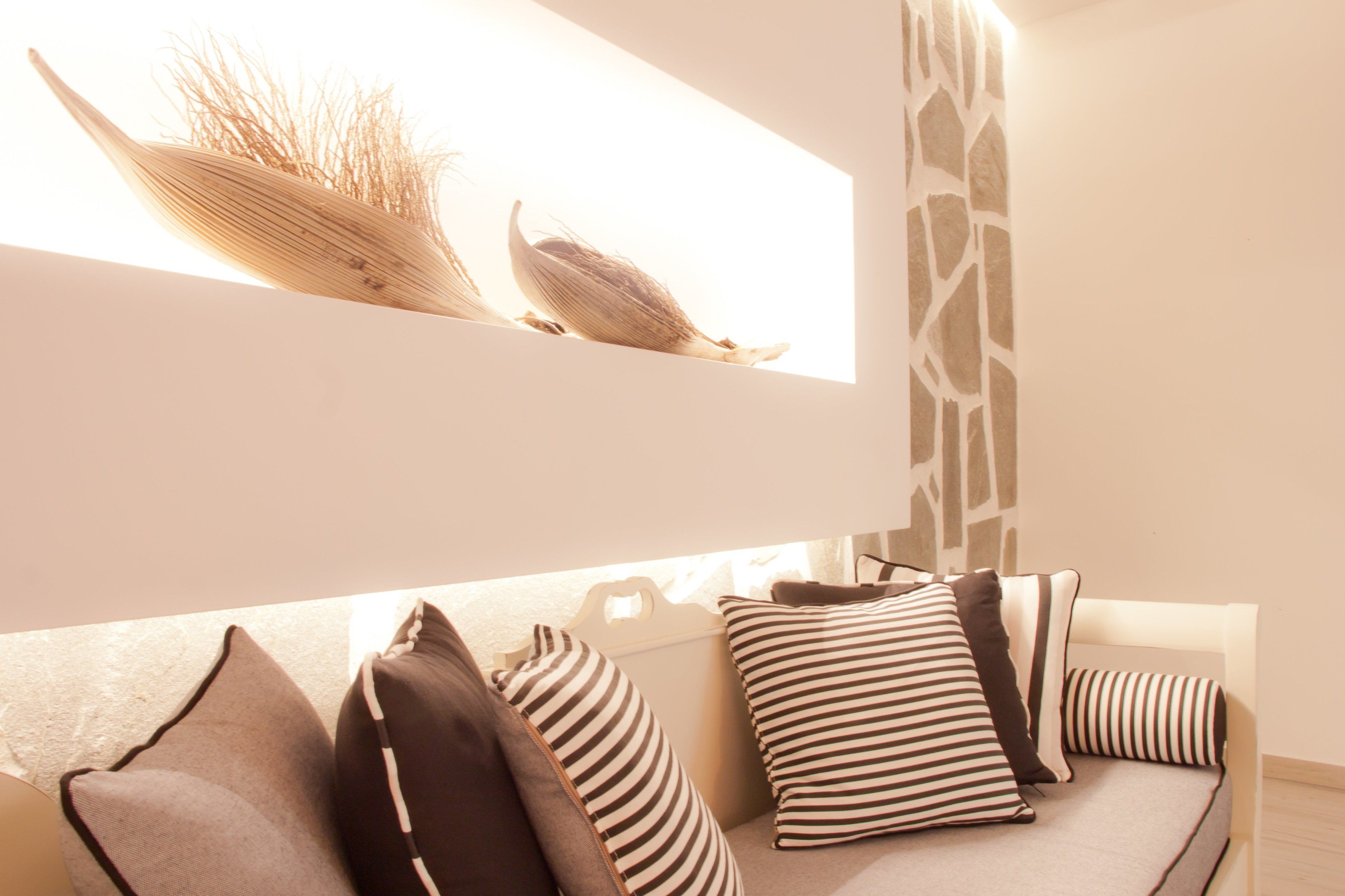 Una sala moderna con un sofá, almohadas a rayas y objetos decorativos en una pared.