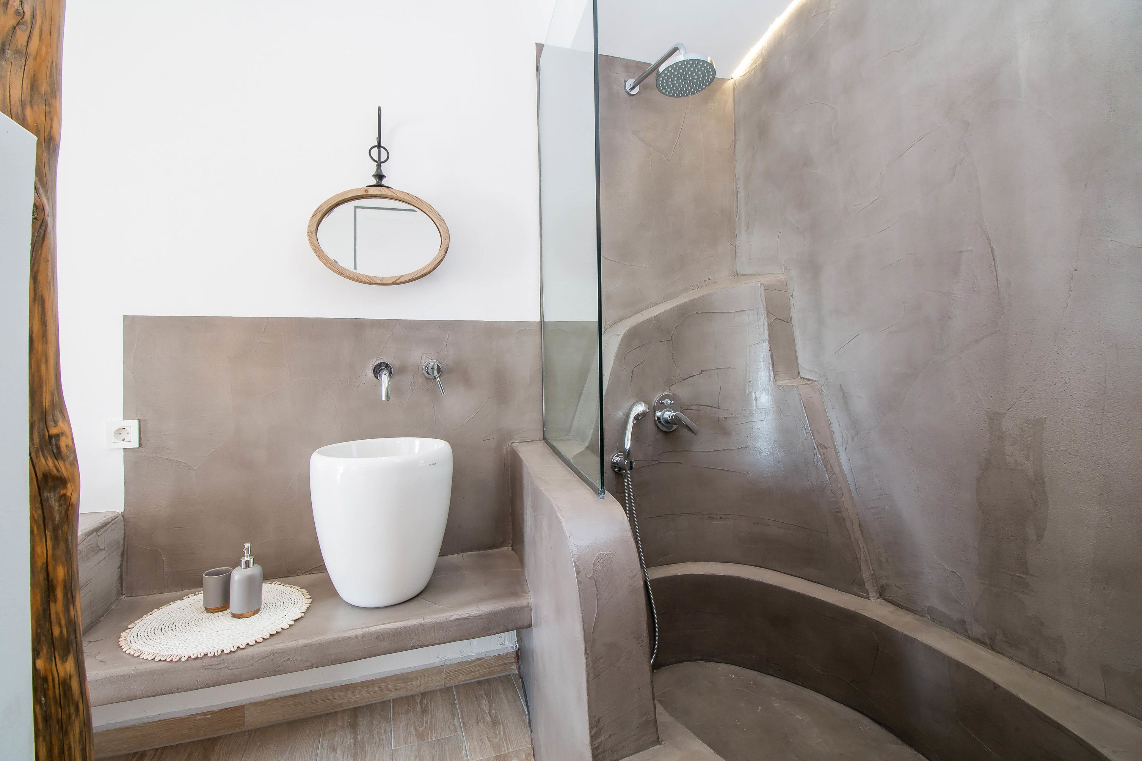 A bathroom with a large white sink, a glass-enclosed shower, and a wooden-framed mirror.
