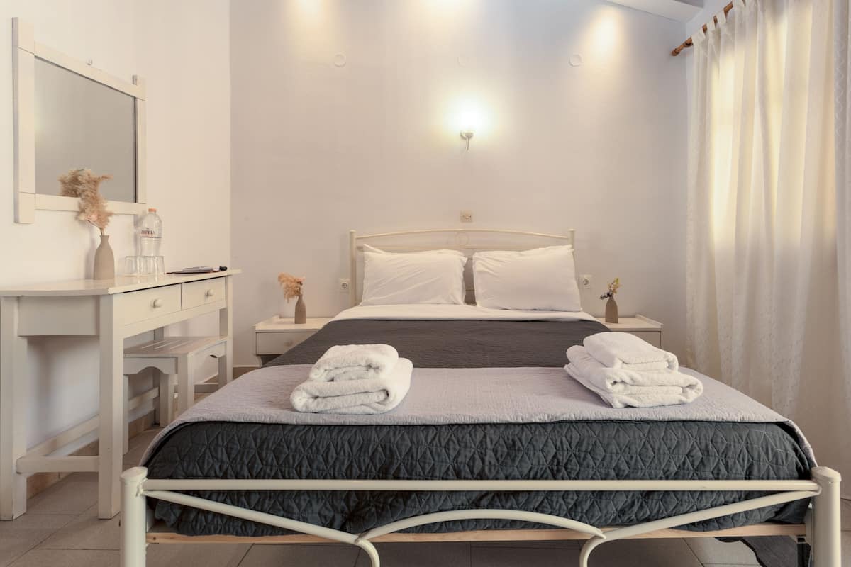 A bedroom with a bed, bedside tables, a dresser, a mirror, and a wall-mounted light.