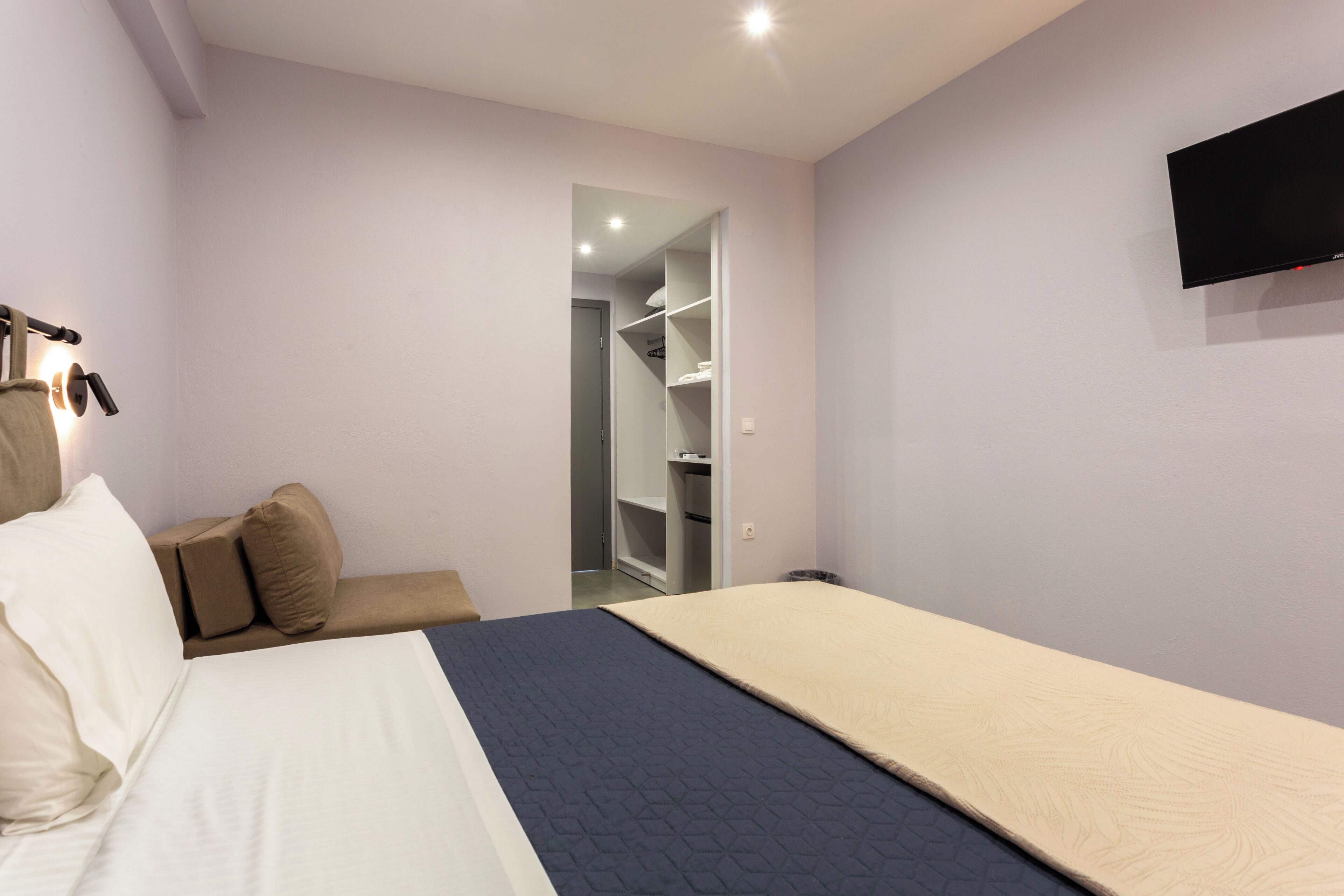 Un dormitorio con cama, sofá, televisión y armario.