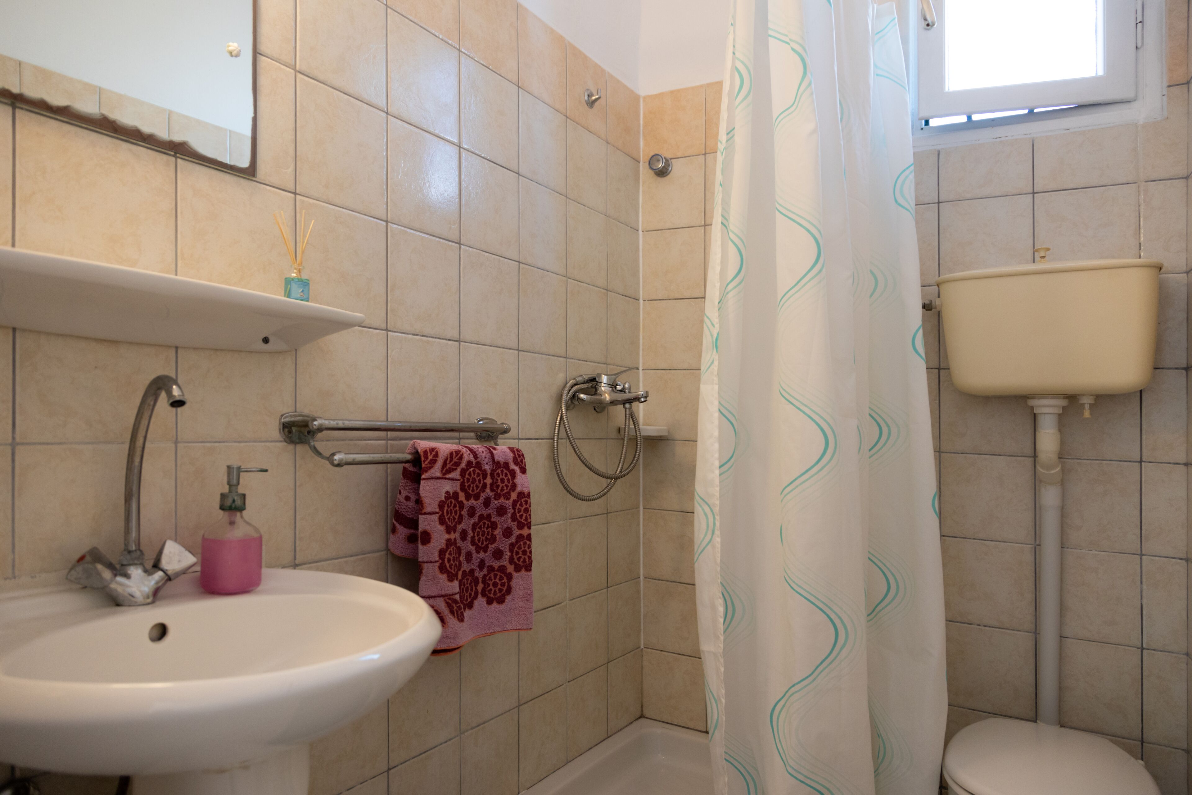 A bathroom with a sink, mirror, shower, and toilet.