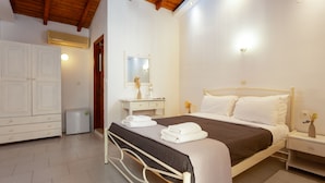 Une chambre à coucher comprenant un lit, une table de chevet, une commode, une armoire et un miroir.