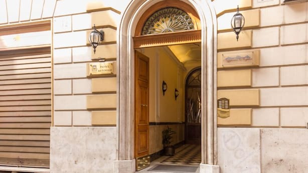 L’entrée d’un hôtel, avec un sol à carreaux, une porte en bois et un éventail décoratif au-dessus de la porte.