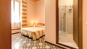 Une chambre d’hôtel avec un lit, une douche et un sol à motifs.