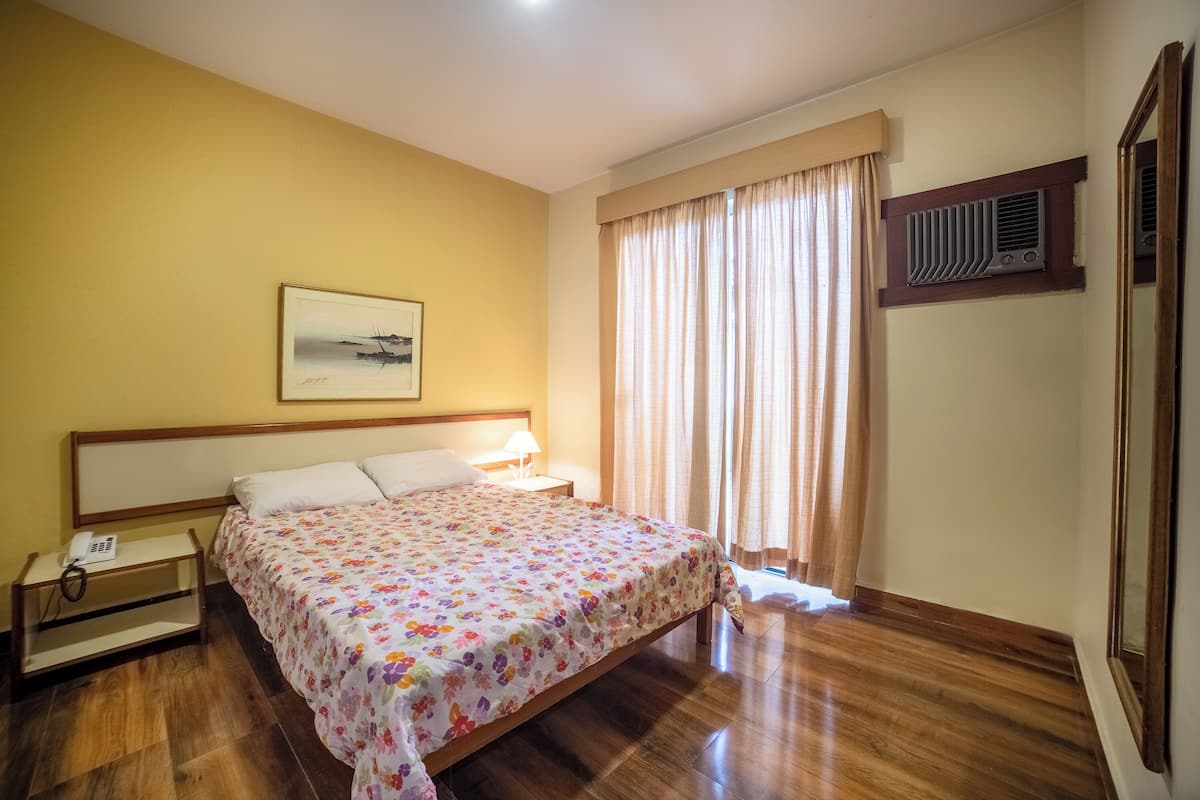 A neatly arranged bedroom with a bed, bedside lamp, and a telephone on a nightstand.