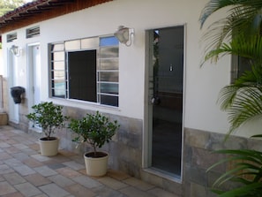 A building with a tiled roof, a door with a glass panel, and two potted plants on the ground. - Hotel Solaris (Sao Lourenco)