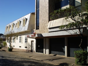 A building with a sign reading "HOTEL SOLARIS." It features a modern architectural style with a mix of materials, including a tiled facade and a glass window. There is a tree in front of the building, and the ground appears to be paved. - Hotel Solaris (Sao Lourenco)