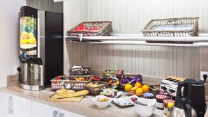Een aanrecht met een koffieapparaat, manden met brood, fruit en toevoegingen.