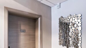 Een moderne hal met een houten deur met het nummer '11', een kamerbreed tapijt en een spiegelbeeld kunstwerk aan de muur.