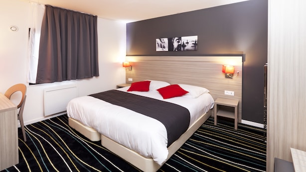 Een moderne hotelkamer met een groot bed, twee nachtkastjes met lampen, een bureau en een stoel.
